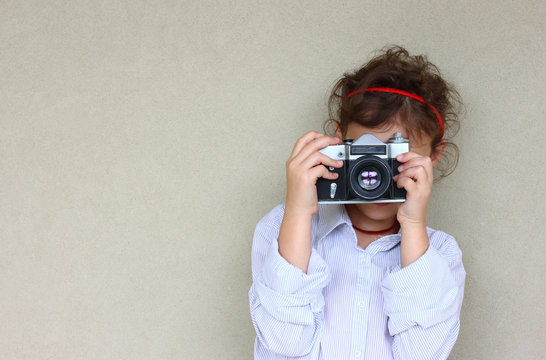 cute kid photographer holding vintage camera during playing acti