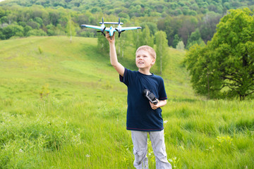 Happy boy with plane on a meadow in a sunny day.