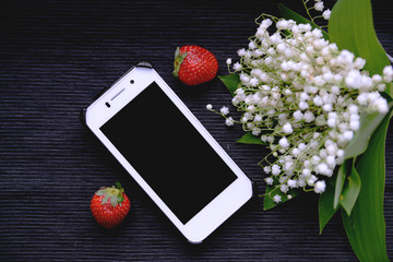 White mobile phone and lily of the valley bouquet