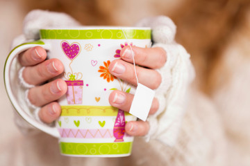 Female hands holding mug of tea.