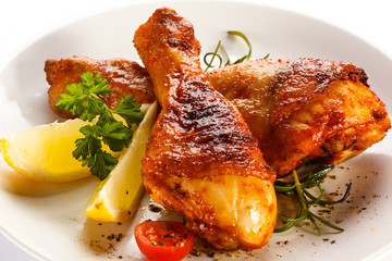 Grilled chicken legs and vegetables on white background