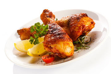 Grilled chicken legs and vegetables on white background
