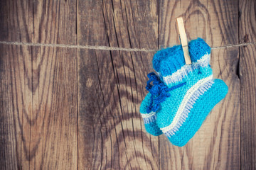 knitted baby socks hanging on clothesline against wooden backgro