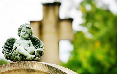 Engel auf Grabstein vor Kreuz