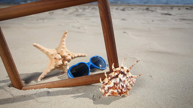 Frame with seashell, starfish and sunglasses on the beach