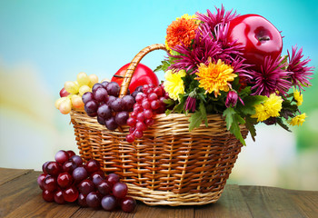 Composition with beautiful flowers in wicker basket and fruits,