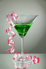 Glass of cocktail and streamer after party on gray background