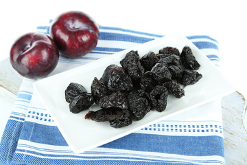 Fresh and dried plums  on wooden board, isolated on white