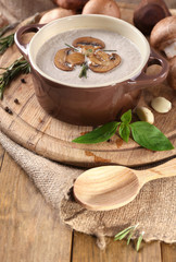Mushroom soup in pot, on napkin,  on wooden background