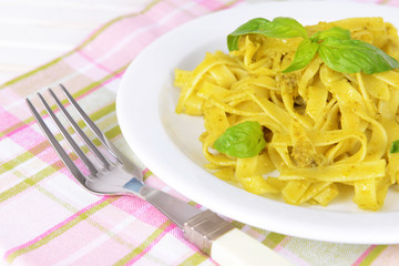 Delicious pasta with pesto on plate on table close-up