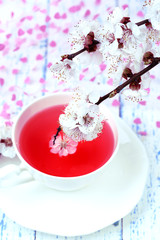 Fototapety  Pachnąca herbata z kwitnącymi gałązkami na drewnianym stole z bliska