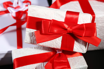 Beautiful gifts with red ribbons, on dark background