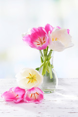 Obraz premium Beautiful tulips in bucket in vase on table on light background