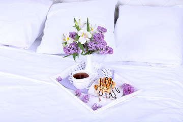 Obraz na płótnie Canvas Wooden tray with light breakfast on bed