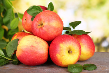 Ripe sweet apples with leaves on nature background
