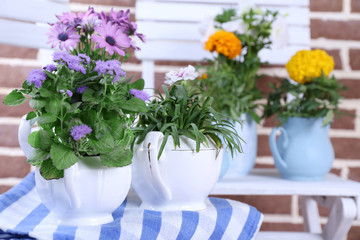 Fototapeta na wymiar Flowers in decorative pots on table, on bricks background