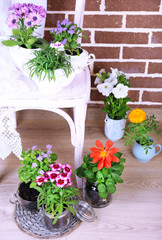 Flowers in  decorative pots on chair, on bricks background