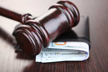 Gavel and money in wallet on wooden background