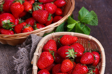 Ripe sweet strawberries in wicker basket and mint leaves