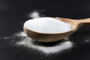 Spoon of baking soda on black background