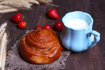 Obraz na płótnie Canvas Ripe sweet strawberries, fresh bun and mug with milk