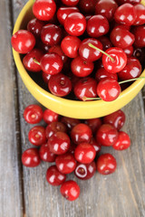 Sweet cherries in mug on wooden background