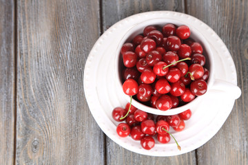 Sweet cherries in mug on wooden background