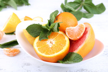 Fresh citrus fruits with green leaves in bowl