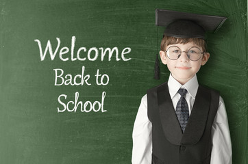 Cheerful little boy on blackboard. Looking at camera