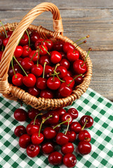Sweet cherries in wicker basket on wooden table