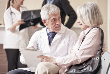 Obraz premium Senior male doctor showing medical results to his female woman p