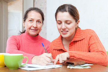 Obraz premium positive women fills in utility payments bills