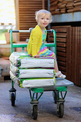 Little girl sitting in shopping cart at gardening hypermarket