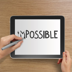 hand changing the word impossible to possible with stylus eraser