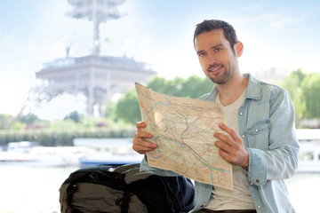 Young attractive tourist reading map in Paris