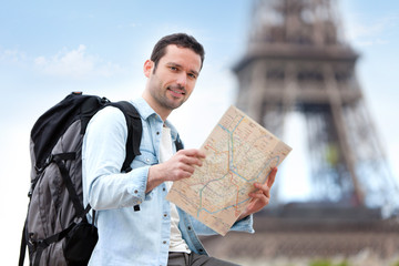 Young attractive tourist reading map in Paris