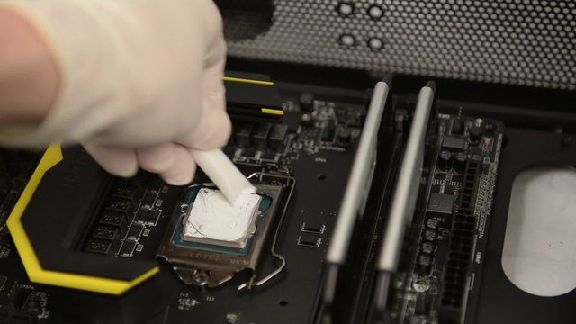 Technitian applies thermal paste on CPU