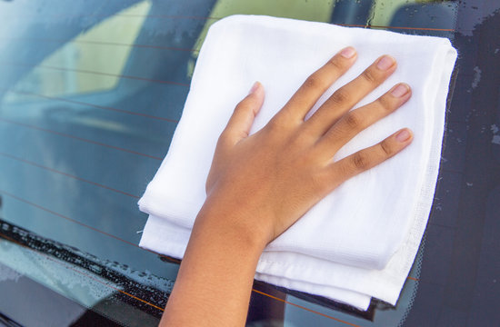 Young girl hand wiping a car glass dry