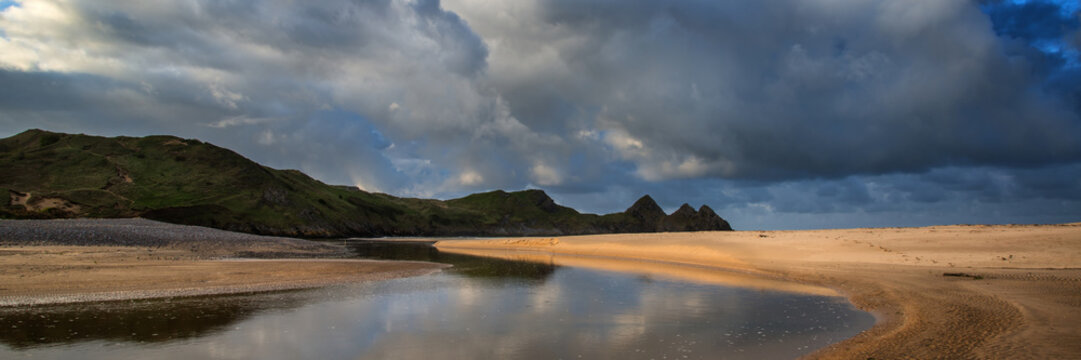 Sunrise landscape panorama Three Cliffs Bay in Wales with dramat