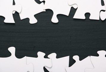A border of blank white jigsaw puzzle pieces on a blackboard