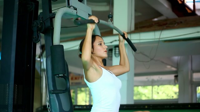Sports young woman doing exercises on Lat Machine.