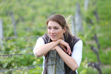 Smiling farming woman standing in vineyard