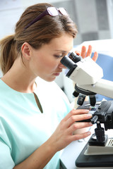 Doctor in laboratory looking through microscope