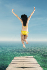 Fototapeta na wymiar Happy woman jumping on the pier
