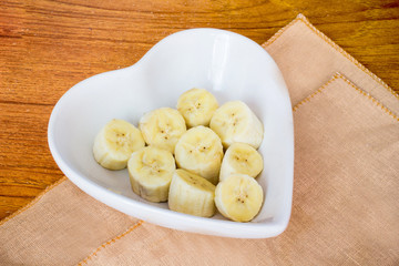 Chopped banana slice on the chopping boar lying on wood table.