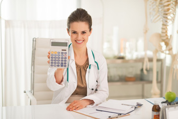 Smiling medical doctor woman showing calculator