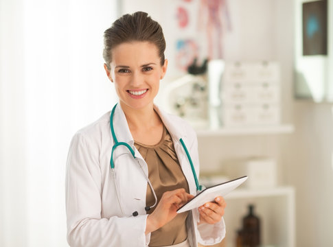 Smiling medical doctor woman using tablet pc