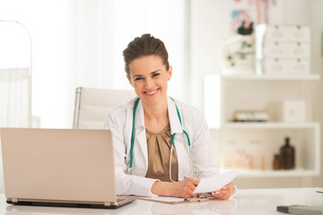 Happy medical doctor woman working in office