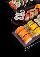 Delicious sushi pieces on black background