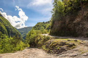 winding road in the mountains against the blue sky and clouds